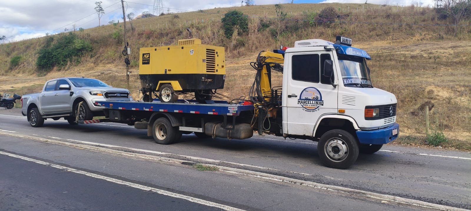 Compressor amarelo e uma picape Ford Ranger prateada na plataforma, na rodovia.